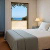 Camera da letto con vista mare, mobili blu e due lampade.