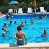Bambino seduto sul bordo di una piscina piena di nuotatori.