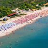Spiaggia affollata con ombrelloni colorati e mare limpido.