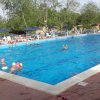 Piscina all'aperto con persone e ombrelloni.