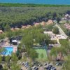 Veduta aerea di un villaggio turistico con piscina e campi sportivi.
