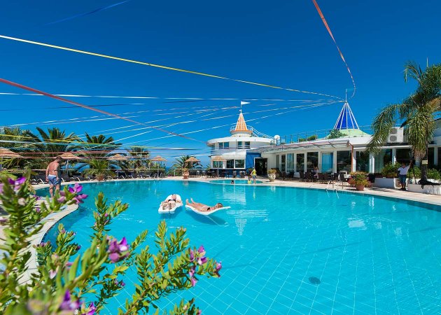 Piscina con persone e nastri colorati nel cielo.