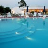 Piscina al tramonto con lettini bianchi e un bar sullo sfondo.