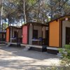 Bungalow colorati in fila tra gli alberi, con piccoli portici.