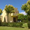 Un edificio giallo con giardino e alberi, mobili da esterno nel prato.