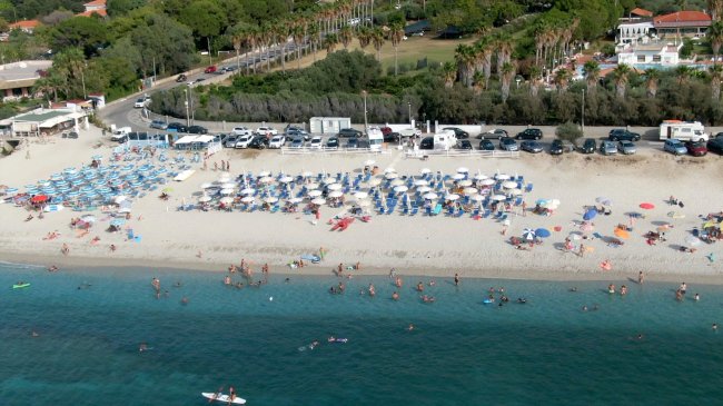 Spiaggia affollata con ombrelloni e mare blu.