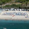 Spiaggia affollata con ombrelloni e mare blu.